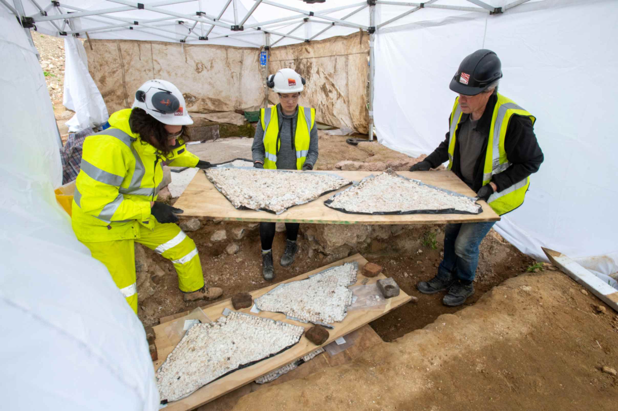 Gli archeologi trasportano con cura i pezzi del mosaico